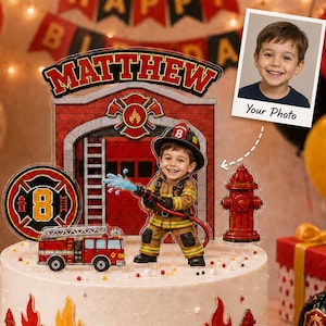 May include: A custom firefighter-themed cake topper set featuring a fire station backdrop with the name Matthew, a child firefighter figure holding a hose, a fire truck, a fire hydrant, and a circular emblem with the number 8, all on a cake.