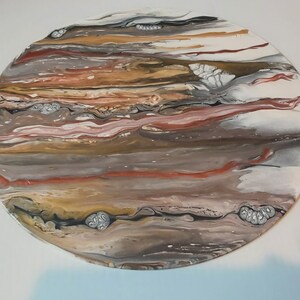 May include: A round, abstract painting with swirling patterns in shades of brown, red, white, and gray. The painting has a textured surface and a circular shape.
