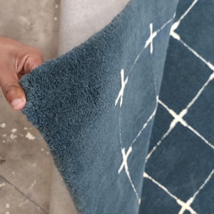May include: A deep blue area rug with a thick, tufted pile texture. The rug features a white grid pattern consisting of intersecting lines that form diamond shapes across the surface. The material appears soft and dense with a visible pile height.