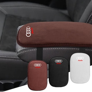 May include: A brown velvet car armrest cover featuring the white Audi logo and red text. Below, three separate rectangular covers are displayed in brown, black, and white, each featuring the white Audi logo and red text branding.