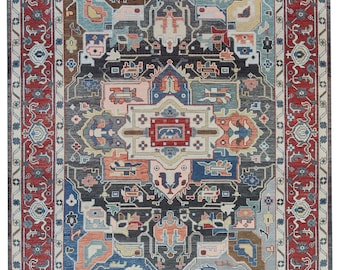 May include: A rectangular area rug featuring a dark charcoal central field with a complex geometric medallion in shades of red, blue, cream, and peach. The rug is framed by a wide red border decorated with intricate floral and vine motifs.