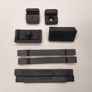 May include: A collection of black rubber automotive components including two small mounting brackets with holes, two rectangular blocks, and four elongated strips. Two of the strips feature the molded text 51484-50080 on their surface.