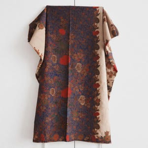 May include: A rectangular textile featuring a central dark blue panel densely patterned with small white, orange, and red floral motifs. The fabric is bordered by wide, light beige side panels decorated with intricate brown and red floral designs.