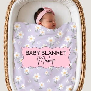 May include: A light purple baby blanket featuring a repeating pattern of white flowers with yellow centers and green stems. A pink scalloped label is centered on the blanket with the black text BABY BLANKET Mockup printed on it.