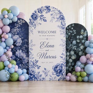 May include: Three arched wedding welcome signs featuring blue and white floral patterns. The center sign displays the text WELCOME TO OUR WEDDING ELENA and Marcus MAY 24, 2025. Clusters of light blue, lavender, and green balloons frame the side panels.