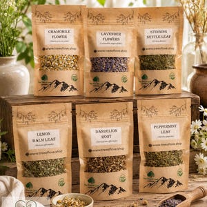 May include: Six brown kraft paper pouches containing dried herbs and flowers, labeled Chamomile Flower, Lavender Flowers, Stinging Nettle Leaf, Lemon Balm Leaf, Dandelion Root, and Peppermint Leaf, with a wooden scoop and a small ceramic bowl.