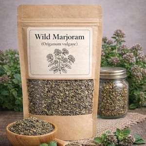May include: A brown kraft paper pouch labeled Wild Marjoram (Origanum vulgare) with a clear window showing dried green herbs. Beside it sits a wooden bowl filled with the same herbs, a small wooden spoon, and a glass jar of dried herbs.