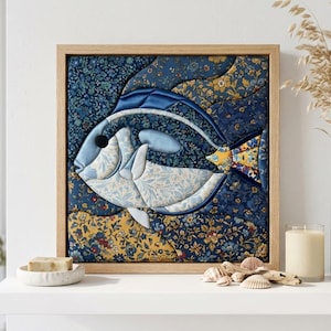 Puede incluir: Una pieza de arte mural de tela enmarcada de forma cuadrada que presenta un pez estilizado compuesto por varios parches de tela con patrones florales azules, blancos y amarillos. El pez se sitúa sobre un fondo floral azul oscuro, en un marco de madera clara.