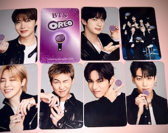 Op de afbeelding: Een verzameling van acht rechthoekige fotokaarten met leden van de muziekgroep BTS. Zeven kaarten tonen individuele leden die een paars Oreo-koekje vasthouden, terwijl één kaart het BTS Oreo-logo en een paarse lightstick-afbeelding toont.