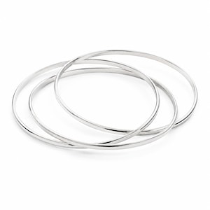 Könnte beinhalten: Ein Set aus drei ineinandergreifenden silberfarbenen Armreifen. Jeder Armreif hat eine glatte, polierte und abgerundete Metalloberfläche. Die drei Reifen sind in einer leicht überlappenden kreisförmigen Anordnung positioniert und bilden ein durchgehendes Design.