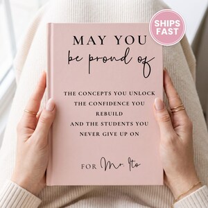 May include: A light pink hardcover book with black text that reads: MAY YOU be proud of THE CONCEPTS YOU UNLOCK THE CONFIDENCE YOU REBUILD AND THE STUDENTS YOU NEVER GIVE UP ON FOR Mr. Ito. The cover features a smooth, matte finish.