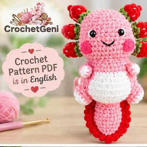 Peut inclure: Une peluche axolotl crochetée rose et blanche avec des branchies rouges en forme de fraise. Un panneau festonné rose clair affiche le texte CrochetGeni Crochet Pattern PDF is in English. Le design présente des yeux noirs et un ventre blanc.