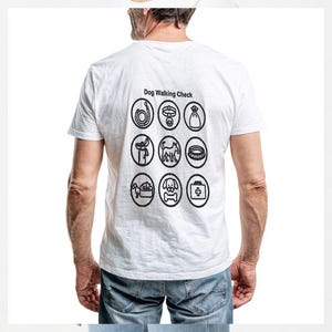 Peut inclure: Un t-shirt blanc à manches courtes avec un motif noir au dos. Le motif comprend le texte Dog Walking Check au-dessus d'une grille de neuf icônes circulaires représentant divers objets liés aux chiens comme une laisse, un collier et un sac.