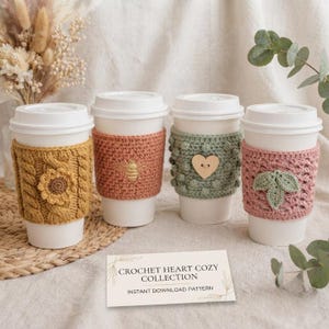 Può includere: Quattro bicchieri da caffè bianchi usa e getta con manicotti in uncinetto testurizzato. I manicotti sono giallo senape con un girasole, terracotta con un'ape, verde salvia con un bottone a cuore in legno e rosa polvere con foglie. Un cartoncino riporta CROCHET HEART COZY COLLECTION.