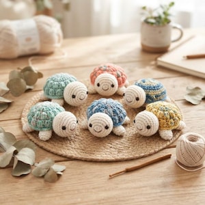Peut inclure: Six petites tortues crochetées à la main disposées en cercle. Chaque tortue présente une tête couleur crème avec des yeux noirs et une carapace texturée et multicolore dans des tons vert menthe, pêche, bleu et jaune, faite de fil.