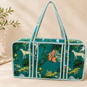 May include: A rectangular quilted tote bag in deep teal featuring a repeating pattern of cheetahs, tropical foliage, and orange flowers. The bag has structured sides and handles with a white and teal striped trim along all edges.