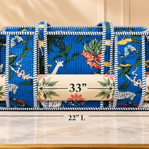 May include: A blue quilted tote bag with a jungle animal print featuring giraffes and zebras, accented by white and blue striped trim. The bag measures 22 inches long, 11 inches high, and 6 inches wide, holding a 33-inch rolled mat.