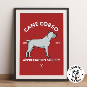 May include: A framed poster with a red background featuring a light grey Cane Corso dog illustration. The text reads CANE CORSO, BEST DOG, and APPRECIATION SOCIETY. A small circular logo at the bottom shows a dog face with the text DRAWING THE DOG.