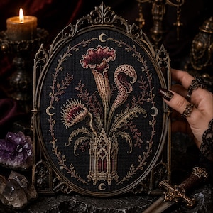 May include: An oval-shaped cross-stitch embroidery featuring a dark fabric background with a central design of carnivorous plants in shades of deep red and gold, housed in an ornate, dark metallic frame with intricate gothic-inspired architectural details.