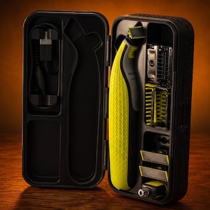 Può includere: Un rasoio elettrico Philips OneBlade in una custodia nera. Il rasoio verde lime e nero è posizionato verticalmente insieme a vari accessori, tra cui un cavo di ricarica, diversi pettini in plastica e una testina per rifinitore naso.