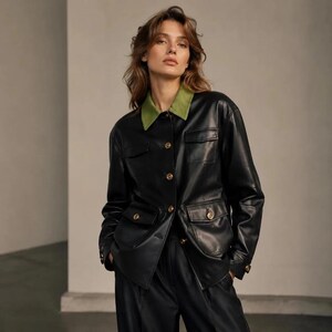 May include: A black long-sleeved jacket with a contrasting olive green collar. The jacket features a button-down front with metallic gold buttons, two chest pockets with flaps, and two lower pockets with flaps, all secured with matching gold buttons.