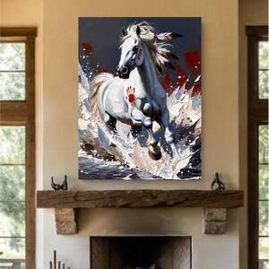 Peut inclure: Une impression d'art mural verticale représentant un cheval blanc galopant dans l'eau. Le cheval porte une empreinte de main rouge sur l'épaule, des marques rouges sur le visage et des plumes dans la crinière. Le fond est sombre avec des éclaboussures de peinture rouge et blanche.