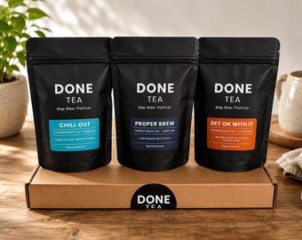 May include: Three black stand-up pouches of Done Tea on a cardboard box. The left pouch has a blue label reading Chill Out, the center has a dark blue label reading Proper Brew, and the right has an orange label reading Get On With It.