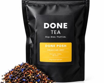 May include: A black resealable pouch of Done Tea with a label reading Done Tea, Stop. Brew. That'll do., Done Posh, Cream Earl Grey, Bold grey, Vanilla, Bit fancy, 50g loose leaf tea. A pile of loose leaf tea with blue and orange petals sits nearby.