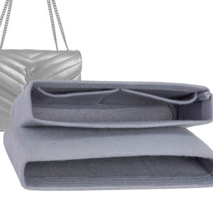 May include: A gray felt bag organizer with multiple compartments for a handbag. The organizer is folded in half and has a light gray color.