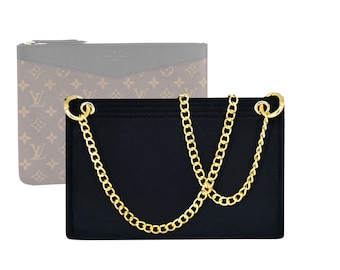 Puede incluir: Clutch negra con una correa de cadena dorada. La bolsa tiene un cierre de solapa y un exterior liso y texturizado.