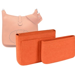 May include: Two orange felt bag organizers for a handbag. The larger organizer has a single large pocket and a smaller pocket on the side. The smaller organizer is a single pocket.