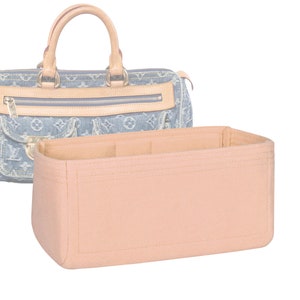 May include: A light pink felt bag organizer with multiple compartments for a handbag. The organizer is designed to fit inside a handbag to help keep it organized.