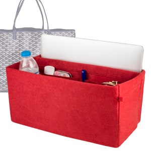 May include: A red felt handbag organizer with multiple compartments, holding a laptop, water bottle, pen, and other small items. A gray tote bag with a geometric pattern is in the background. The organizer is designed to keep items neat.