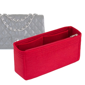 May include: Red felt bag organizer with a zipper closure and multiple compartments. The organizer is designed to fit inside a handbag.