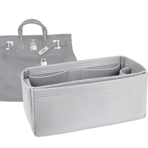 Puede incluir: Un organizador de bolso de fieltro gris con múltiples compartimentos para un bolso de mano. El organizador tiene una forma rectangular y está diseñado para caber dentro de un bolso más grande.