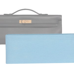 May include: A light blue felt bag insert for a handbag. The insert has a stitched border and is designed to help keep the bag organized.
