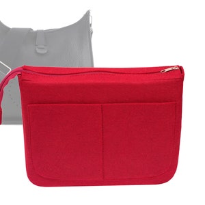 May include: Red felt bag organizer with a zipper closure and two large pockets. The organizer is designed to fit inside a larger bag.