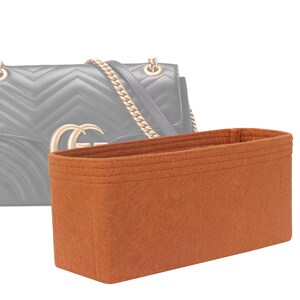 Peut inclure: Un insert de sac en feutre marron pour un sac à main. L'insert a une forme rectangulaire et est conçu pour aider à organiser le sac.