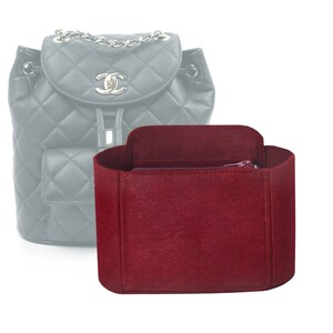 May include: A burgundy felt bag organiser with a zipped pocket. The organiser is designed to fit inside a quilted backpack.