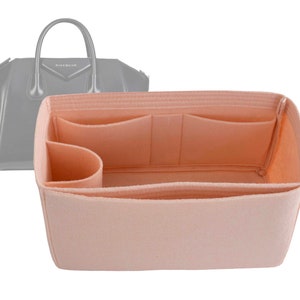 Puede incluir: Un organizador de bolso de fieltro rosa claro con múltiples compartimentos y bolsillos. El organizador está diseñado para caber dentro de un bolso de mano.