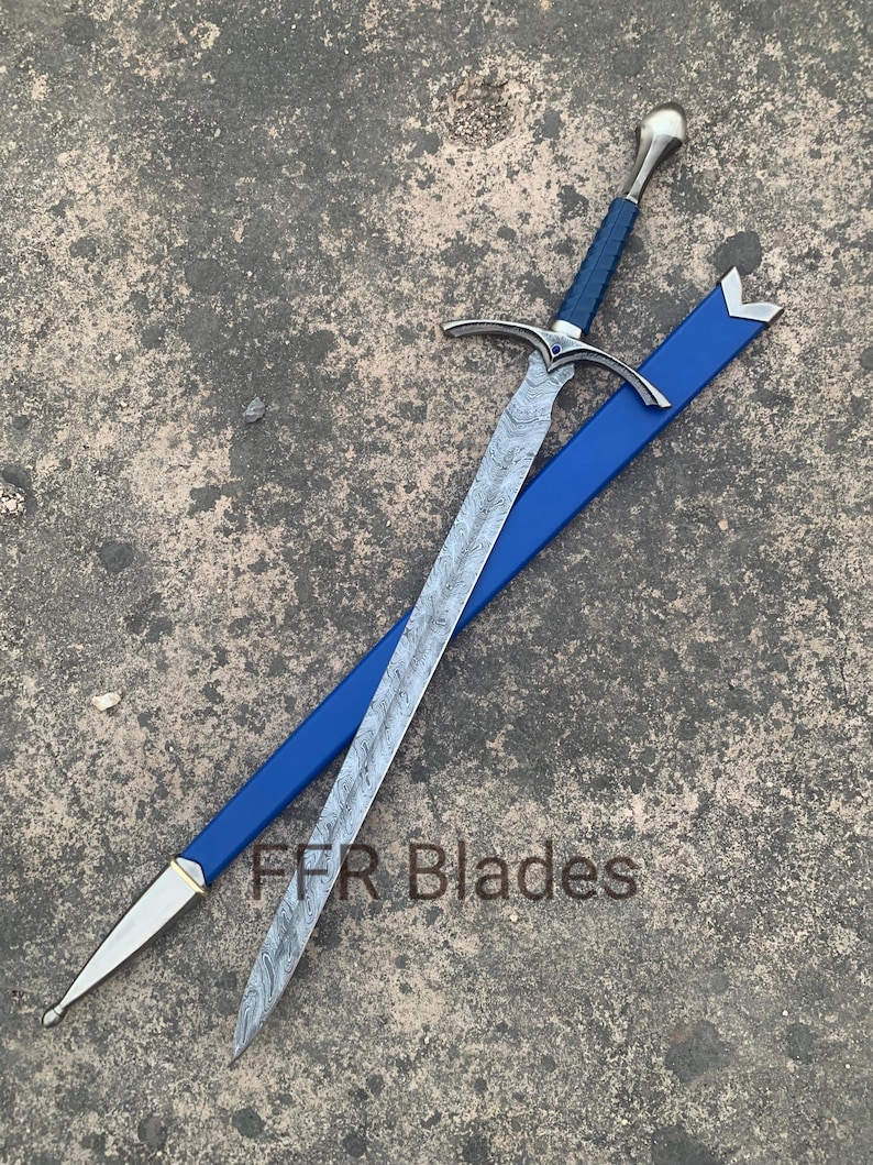 May include: A sword with a patterned Damascus steel blade, a blue wrapped handle, and a silver pommel. The crossguard features a small blue stone. It is accompanied by a blue scabbard with silver accents. The text FFR Blades is visible.