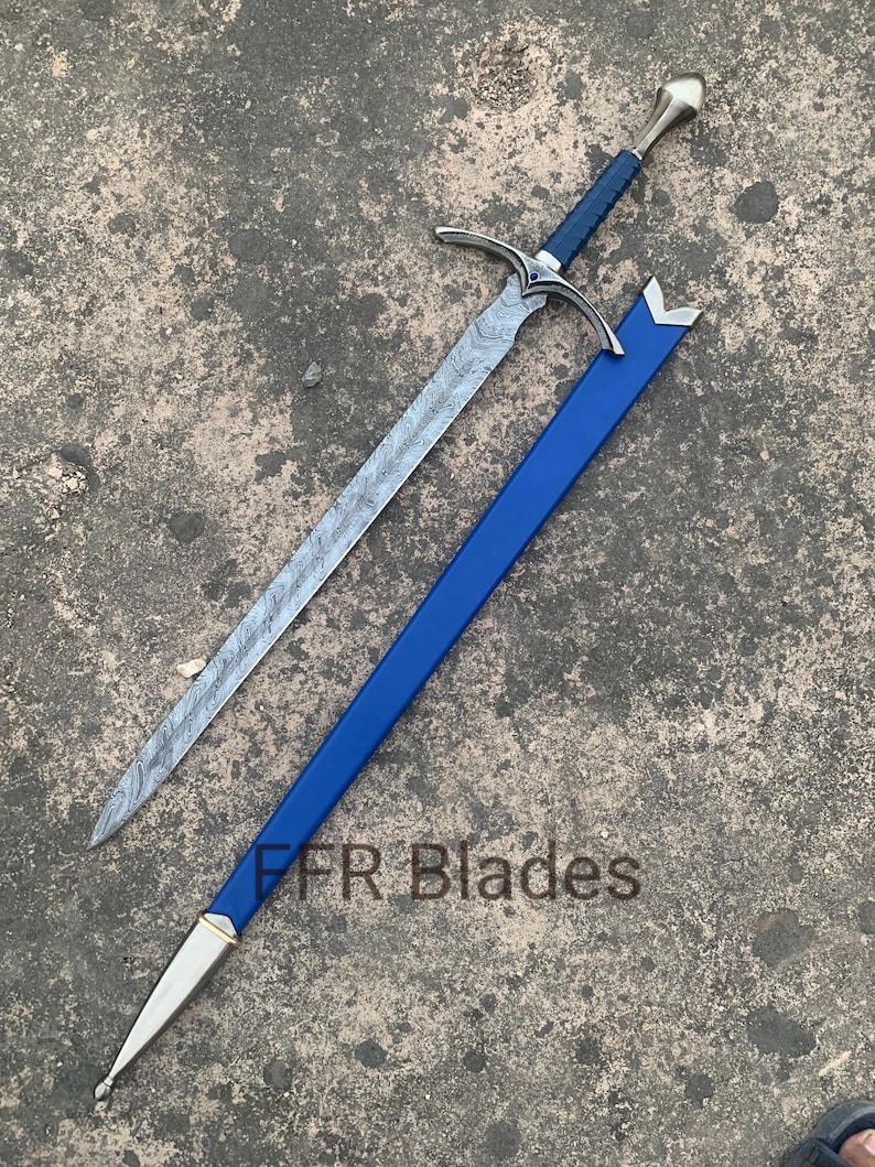 May include: A sword with a patterned Damascus steel blade, a blue leather-wrapped handle, and a silver-toned pommel and crossguard. The sword is accompanied by a blue scabbard with silver-toned metal fittings. The text FFR Blades is visible.