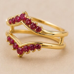 Peut inclure: Une bague en or avec un design &agrave; double chevron. Chacune des deux bandes en forme de V est sertie d'une rang&eacute;e de petites pierres pr&eacute;cieuses rondes d'un rouge &eacute;clatant. Le m&eacute;tal dor&eacute; poli forme un cadre lisse autour des pierres facett&eacute;es.