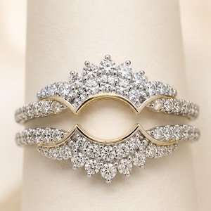 May include: A two-piece ring guard set featuring a curved design with round clear stones set in silver-toned metal. The bands are accented with thin gold-toned metal lines that follow the arch, creating a layered look with pavé-set stones.