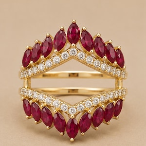 May include: A gold ring guard featuring two chevron-shaped bands. The top band is adorned with marquise-cut red rubies and a row of round white diamonds. The bottom band mirrors this design with matching rubies and diamonds in a symmetrical arrangement.