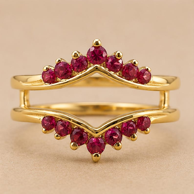 Peut inclure: Une bague double en or avec deux bandes en forme de chevron reli&eacute;es par des barres verticales. La bande sup&eacute;rieure est orn&eacute;e de sept rubis ronds rouge fonc&eacute;, et la bande inf&eacute;rieure comporte sept rubis ronds rouge fonc&eacute; assortis sertis.