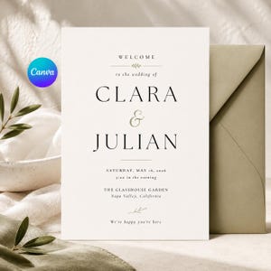 May include: A white wedding invitation card with black serif text reading Welcome to the wedding of Clara & Julian, Saturday, May 16, 2026, 5:00 in the evening, The Glasshouse Garden, Napa Valley, California, and We're happy you're here.