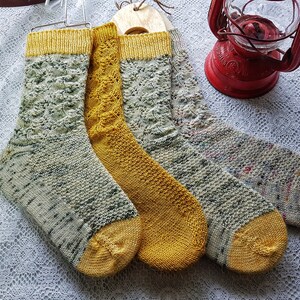 May include: Four pairs of knitted socks, two pairs are yellow and two pairs are a mix of green, white, and brown.