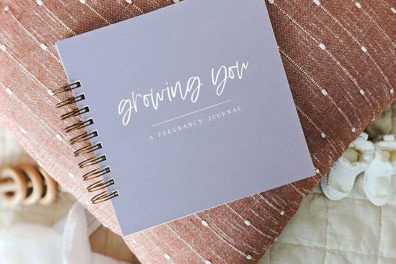 A purple spiral bound journal with the text "Growing You" and "A Pregnancy Journal" on the cover.
