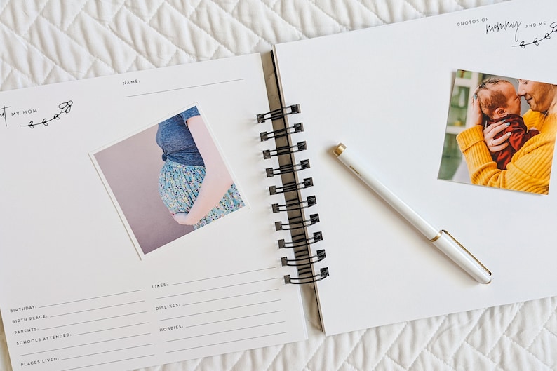 May include: An open white journal with a black spiral binding. The left page has a photo of a pregnant woman and the text "My Mom" with a floral design. The right page has a photo of a mother holding a baby and the text "Photos of Mommy and Me" with a floral design.